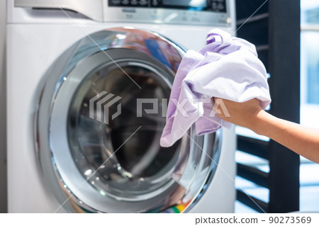 Housewife Woman hand holding clothes inside Washing Machine in laundry room Housewife Woman hand holding clothes inside Washing Machine in laundry room 90273569