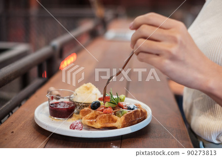Woman eating dessert with fresh berries and fruit at cafe 90273813