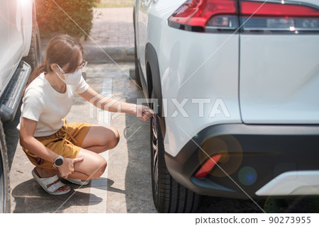 Woman driver hand inflating tires of vehicle, removing tire valve nitrogen cap for checking air pressure and filling air on car wheel at gas station. self service, maintenance and safety 90273955