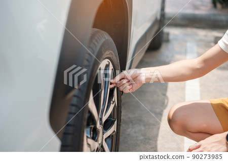 Woman driver hand inflating tires of vehicle, removing tire valve nitrogen cap for checking air pressure and filling air on car wheel at gas station. self service, maintenance and safety 90273985