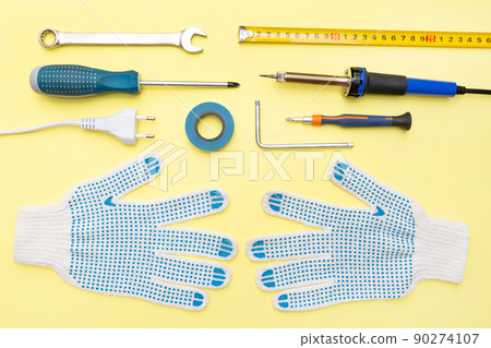 Repair tools on a yellow background. Measuring tape, screwdriver, construction gloves. Flat lay. Top view. Handyman tool kit. DIY. Advertising for the shop. 90274107