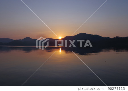 Sunrise scene of the sea The calm sea surface and the low mountains surrounding the bay 90275113