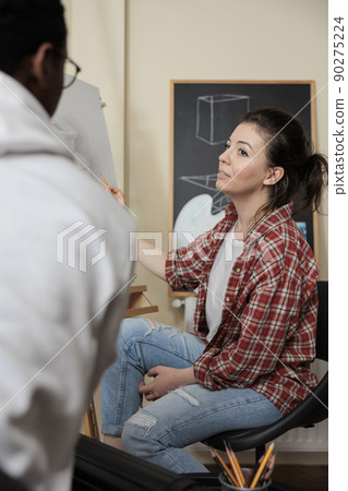 Artist woman working at illustration technique with collegue during art lesson in creativity studio. Diverse team drawing vase model using graphic pencil. New years resolutions concept 90275224