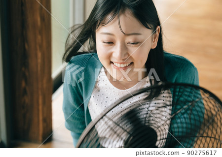 用電風扇的風降溫的年輕女子 90275617