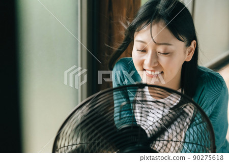 用電風扇的風降溫的年輕女子 90275618
