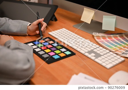 Female freelance graphic designer working at her home office desk. Female freelance graphic designer working at her home office desk. 90276009