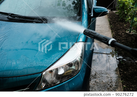 Car wash at home alone. Car wash high pressure close-up. A man washes a green car. Car wash at home alone. Car wash high pressure close-up. A man washes a green car. 90276272