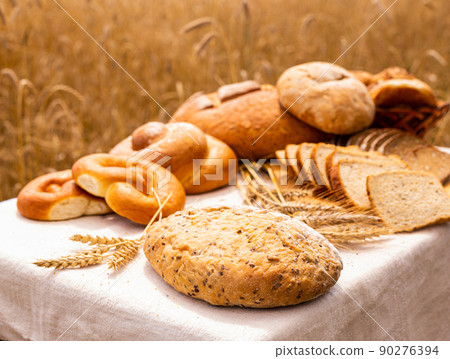 lot of different flavored bread, wheat, rye, on the table in the field outside 90276394