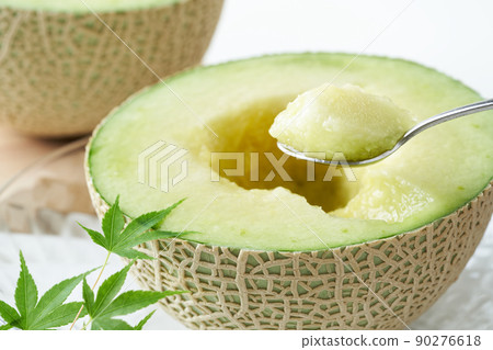 Scoop the Earl's melon cut in half with a spoon 90276618