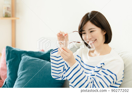 Young woman wearing glasses in the living room Young woman wearing glasses in the living room 90277202