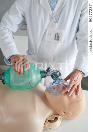 Close-up of paramedic in white coat using oxygen mask to make first aid during medical course 90277227