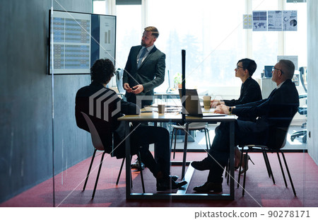 Project manager pointing at desktop presenting statistical data, briefing diverse group of employees at boardroom Project manager pointing at desktop presenting statistical data, briefing diverse group of employees at boardroom 90278171