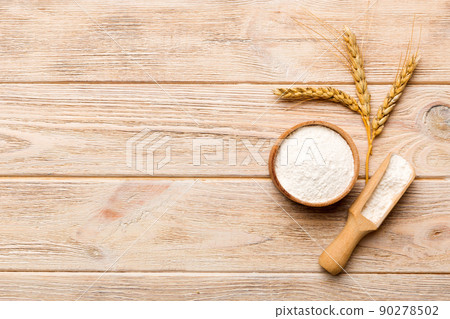 Flat lay of Wheat flour in wooden bowl with wheat spikelets on colored background. world wheat crisis 90278502
