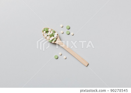 Vitamin capsules in a wooden spoon on a colored background. Pills served as a healthy meal. Drugs, pharmacy, medicine or medical healthycare concept Vitamin capsules in a wooden spoon on a colored background. Pills served as a healthy meal. Drugs, pharmacy, medicine or medical healthycare concept 90278545