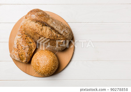 Freshly baked bread on cutting board against white wooden background. top view bread with copy space Freshly baked bread on cutting board against white wooden background. top view bread with copy space 90278858