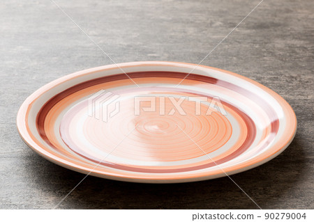 Perspective view of empty orange plate on cement background. Empty space for your design 90279004