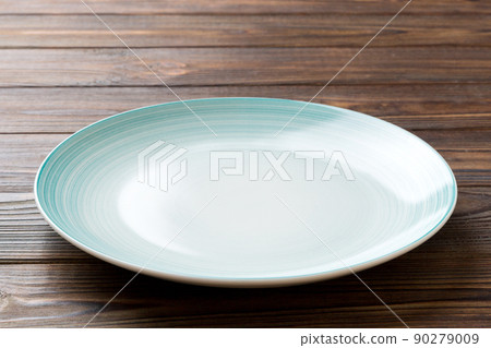Perspective view of empty blue plate on wooden background. Empty space for your design 90279009