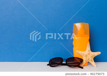 Beach accessories. Moisturiser sunscreen suntan lotion bottle for UVB skincare protection in summer with seashells on colored background. Mock up with copy space 90279073