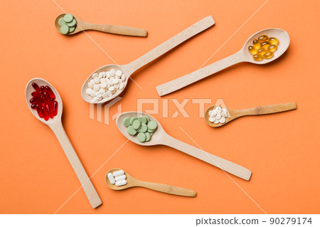 Top view Variety of vitamin and mineral pills in wooden spoon on Colored background. Top view of assorted pharmaceutical medicine pills. Dietary supplement healthcare product Top view Variety of vitamin and mineral pills in wooden spoon on Colored background. Top view of assorted pharmaceutical medicine pills. Dietary supplement healthcare product 90279174