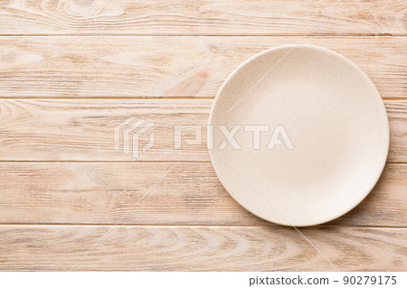 Top view of empty light plate on wooden background. Empty space for your design Top view of empty light plate on wooden background. Empty space for your design 90279175