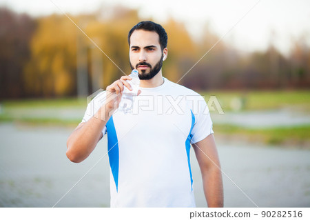 Man doing fitness outdoors listening to music Man doing fitness outdoors listening to music 90282516