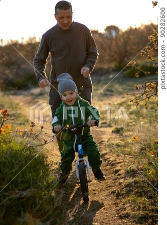 A father and his little son compete which one is faster in the open air. A father and his little son compete which one is faster in the open air. 90282600