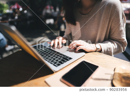 Adult asian woman hand using laptop for work on weekend at outdoor cafe on day 90283956