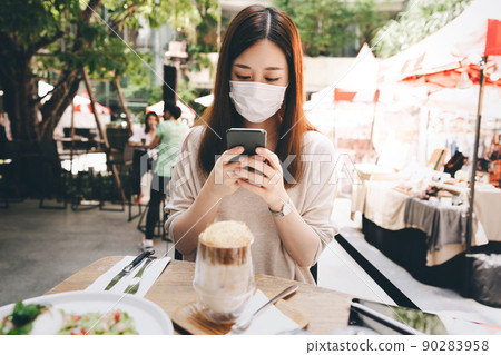 Young adult asian woman wear mask for new normal lifestyle at outdoor restaurant on day Young adult asian woman wear mask for new normal lifestyle at outdoor restaurant on day 90283958
