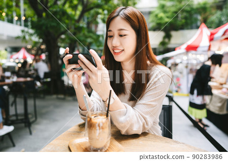 Relax asian woman at cafe using smart phone for social media. 90283986