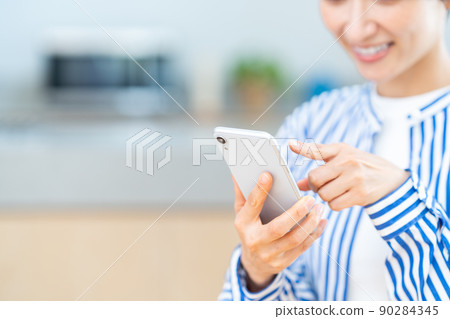 Middle-aged women (parts) who use smartphones in the living room 90284345