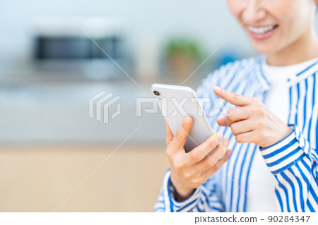 Middle-aged women (parts) who use smartphones in the living room 90284347