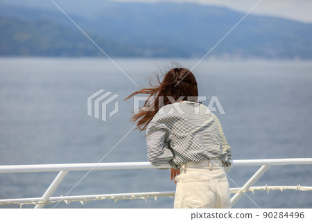 A woman looking out at the sea on the ferry deck 90284496