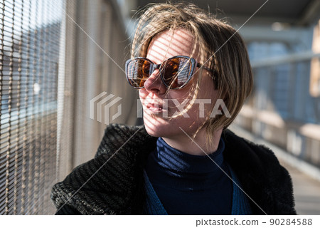 Attractive thirty year old woman with hard shadow lines on her face and sunglasses 90284588