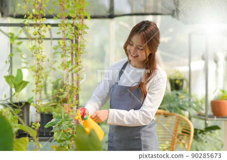 Young woman caring for trees in a greenhouse, planting trees, plant care equipment, planting greenhouses. Young woman caring for trees in a greenhouse, planting trees, plant care equipment, planting greenhouses. 90285673