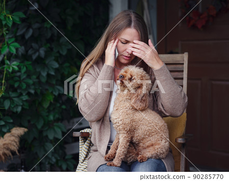 woman sits on terrace with poodle and communicates smartphone. woman sits on terrace with poodle and communicates smartphone. 90285770