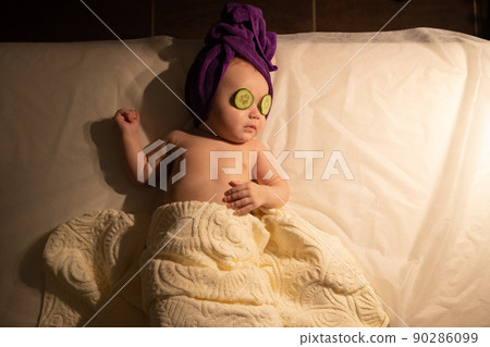 Female little baby infant baby child lying on bed cucumber eyes. 90286099
