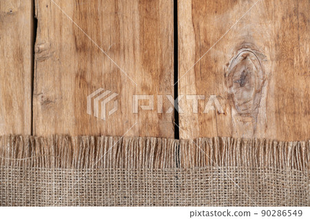 The burlap lies on the tabletop of a wooden table. Rough cloth on top of rough boards. Top view 90286549