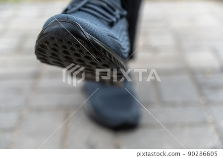 Close-up of male legs in blue sports shoes. Legs of an adult male sitting on an outdoor bench. Daytime. Selective focus. Close-up of male legs in blue sports shoes. Legs of an adult male sitting on an outdoor bench. Daytime. Selective focus. 90286605