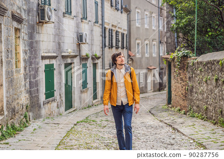 Man tourist on background of Scenic panorama view of the historic town of Risan at famous Bay of Kotor on a beautiful sunny day with blue sky and clouds in summer, Montenegro, southern Europe Man tourist on background of Scenic panorama view of the historic town of Risan at famous Bay of Kotor on a beautiful sunny day with blue sky and clouds in summer, Montenegro, southern Europe 90287756