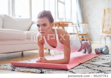 Young healthy active woman training and doing plank at home Young healthy active woman training and doing plank at home 90287761