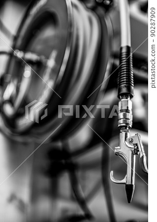 auto-rewinding air hose reel with coiled tubing mounted on a wall in a shop 90287909