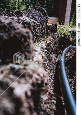 Focus on a black 1 inch sprinkler plastic water line laid in a shallow trench Focus on a black 1 inch sprinkler plastic water line laid in a shallow trench 90287914