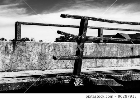 Damaged and bent guardrail along the edge of a bridge that needs repaired. Damaged and bent guardrail along the edge of a bridge that needs repaired. 90287915