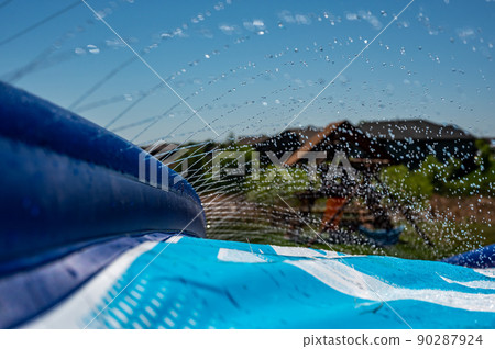 Selective focus on jets of droplets shooting out across a water slide 90287924