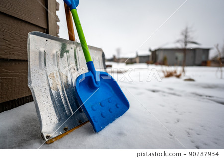 Adult and child snow shovel next to each other Adult and child snow shovel next to each other 90287934