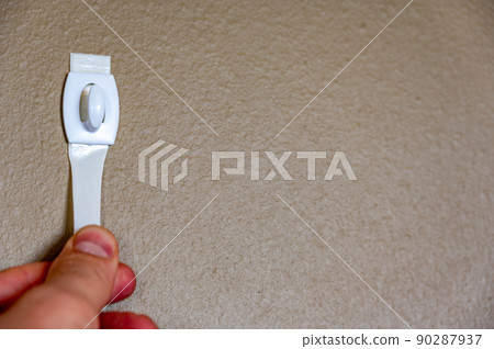 Selective focus on adhesive strip wall hanger that can be removed by pulling tape Selective focus on adhesive strip wall hanger that can be removed by pulling tape 90287937