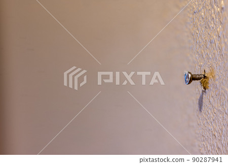 Macro of a single nail protruding from painted drywall in a residential house Macro of a single nail protruding from painted drywall in a residential house 90287941