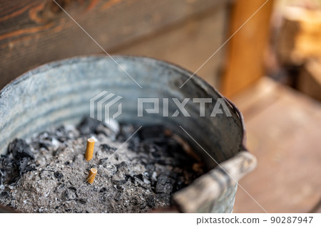 cigarette ash bucket sitting on a wooden porch in a rural setting cigarette ash bucket sitting on a wooden porch in a rural setting 90287947