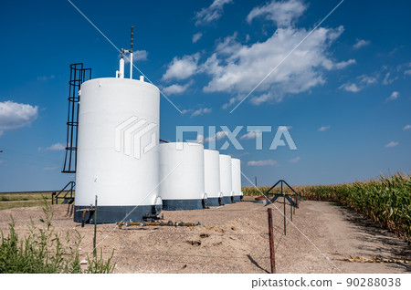 crude oil storage tanks with secondary containment and fencing in a rural corn field 90288038