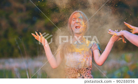 Friends sprinkle their cheerful girlfriend with multi-colored powder. Holi holiday. 90288056